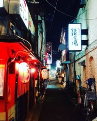 Illuminated street amidst buildings in city at night