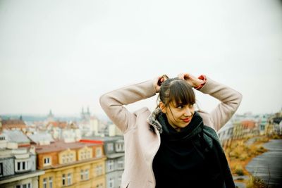 Full length of young woman standing against cityscape