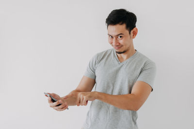 Young man using mobile phone against white background