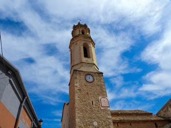 Low angle view of clock tower amidst buildings against sky