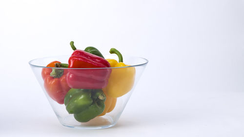 Close-up of bell peppers in glass bowl over white background