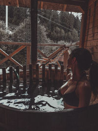 Side view of woman sitting on window