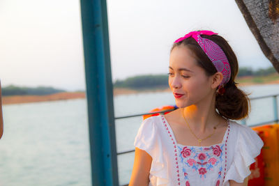 Woman standing by railing against sea during sunset