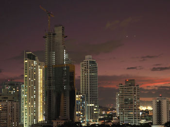 Illuminated buildings in city against sky at night