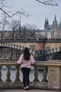 Rear view of woman standing on bridge over river