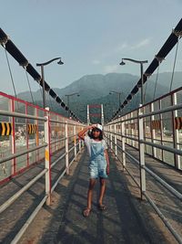 Rear view of man standing on railroad track against sky