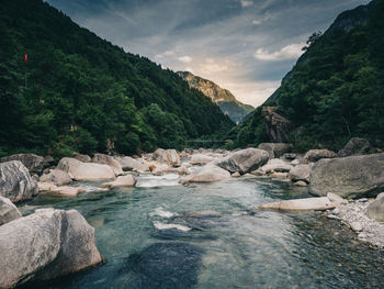 Scenic view of river by mountains against sky