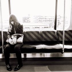 Young woman sitting on window