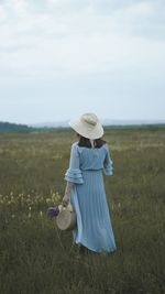 Rear view of woman standing on field against sky