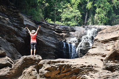 Woman standing on rock against waterfall