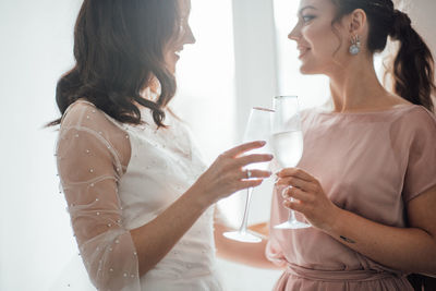 Bridesmaid and bride holding champagne flute