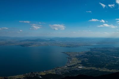 Aerial view of sea and mountains against blue sky