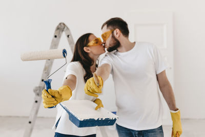 Happy smiling married couple engaged in renovation repair in the room of the house preparing to move