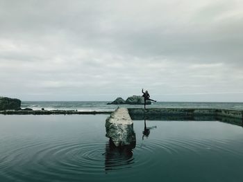 Woman standing in sea against sky