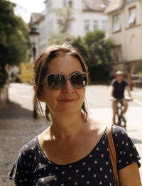 Portrait of young woman with sunglasses on street in city