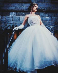 Woman wearing dress while standing against wall