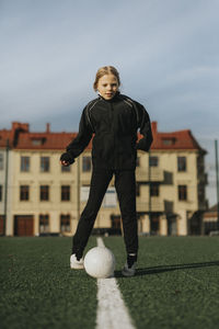 Female athlete playing with soccer ball against sky at sports field