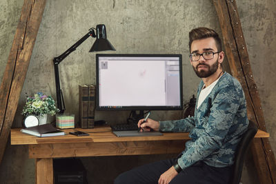 Portrait of man using laptop at office