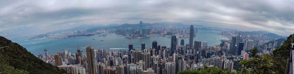 Panoramic view of city buildings against cloudy sky