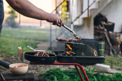 Close-up of person preparing food on barbecue grill