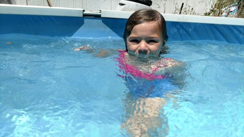 High angle portrait of girl swimming in pool during sunny day