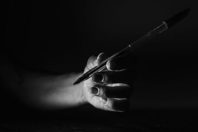 Close-up of hand holding wineglass over black background