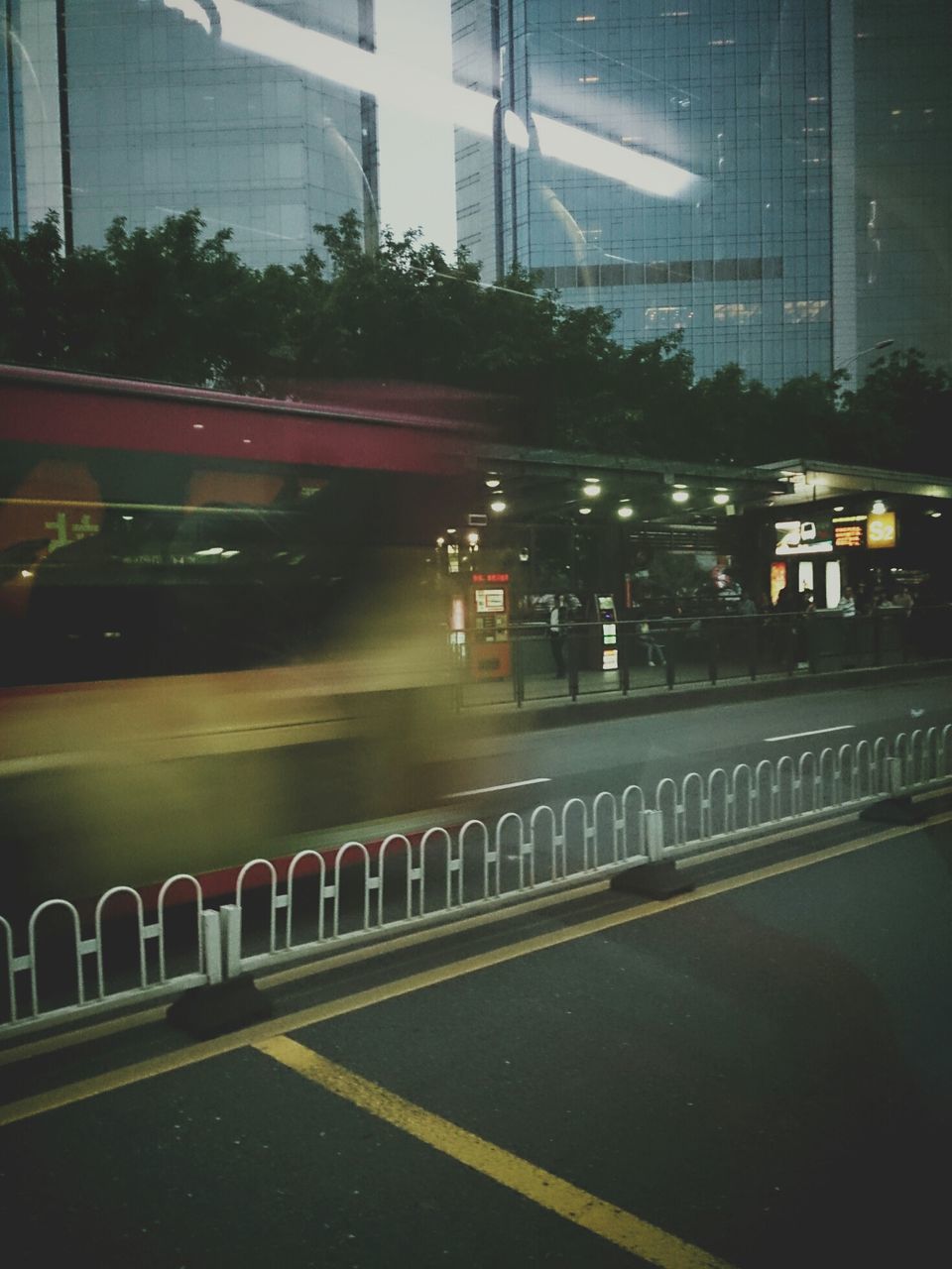 transportation, city, building exterior, architecture, illuminated, road, street, built structure, road marking, night, car, city street, glass - material, city life, reflection, motion, street light, the way forward, building, outdoors