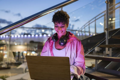 Portrait of smiling woman standing against bridge