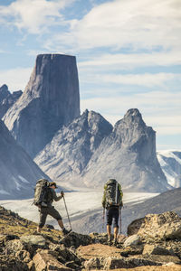 Rear view of people on rock by mountains against sky