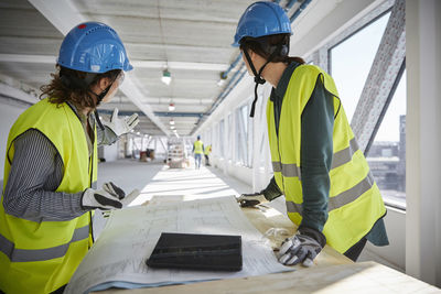 Female engineers planning over blueprint at construction site