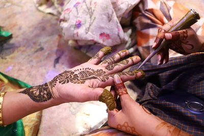 Cropped hand of woman applying henna tattoo at home
