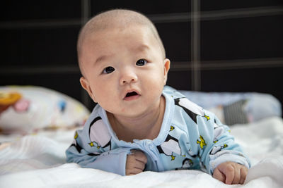 Portrait of cute baby boy lying on bed