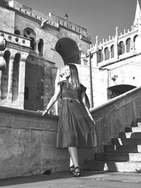 Full length of young woman standing against building