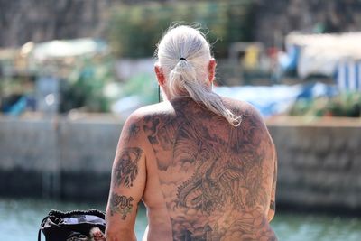 Rear view of shirtless woman against blurred background