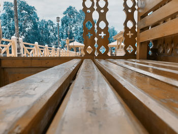 Surface level of wooden bench against sky