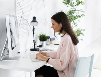 Side view of woman using mobile phone at table