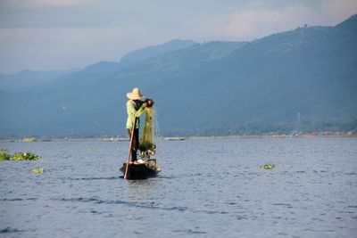 Fisherman fishing on lake against mountains