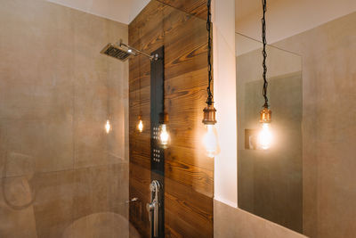 Illuminated lighting equipment hanging on ceiling in the bathroom at home