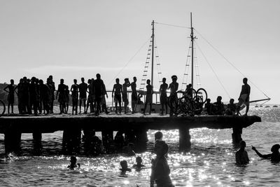 Silhouette people by sea against clear sky