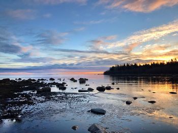 Scenic view of beach against sky at sunset