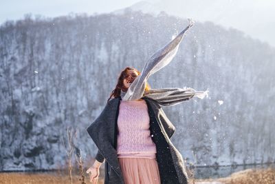 Woman holding umbrella standing at shore