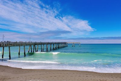 View of pier on beach against blue sky