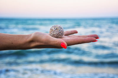 Cropped hand holding stone at beach