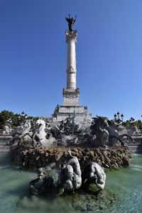 Statues in fountain by monument aux girondins at place des quinconces against clear sky