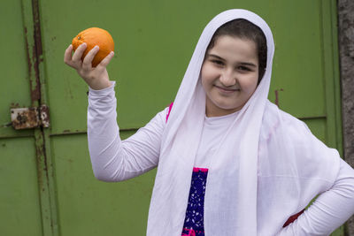 Portrait of smiling young woman standing against orange wall