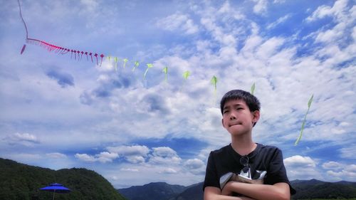 Boy standing against flying kites against sky