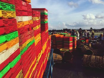 Stack of colorful crates by people at pier