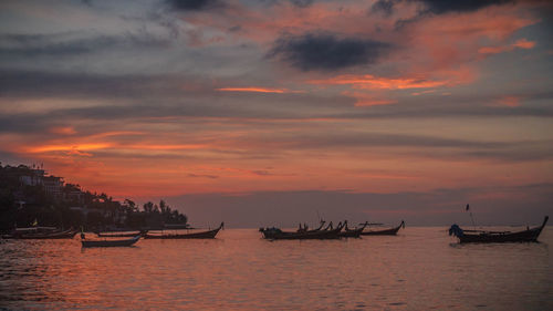 Silhouette boats sailing in sea against sky during sunset