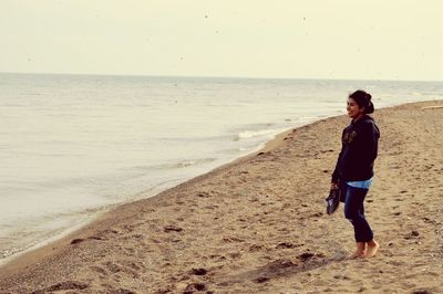 Full length of man standing on beach against clear sky