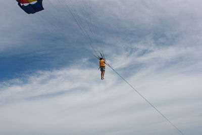 Low angle view of person paragliding against sky